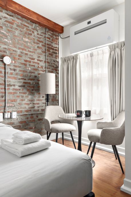 Hotel room — king bed in foreground, windows looking out onto city