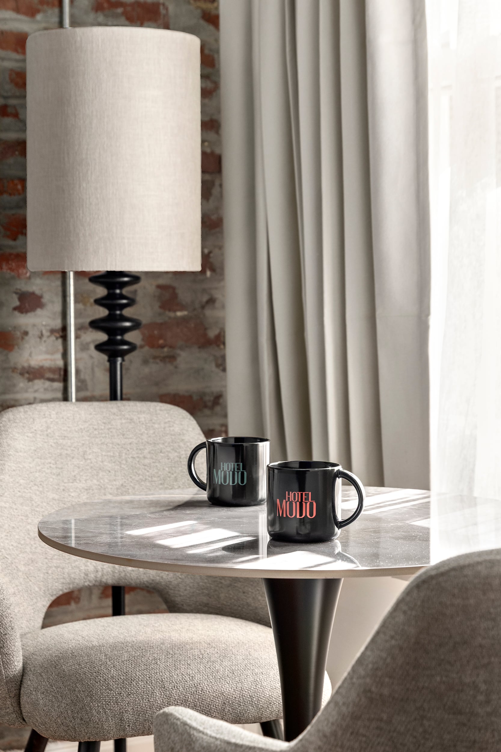 Hotel Modo coffee mugs and in-room coffee set against exposed brick