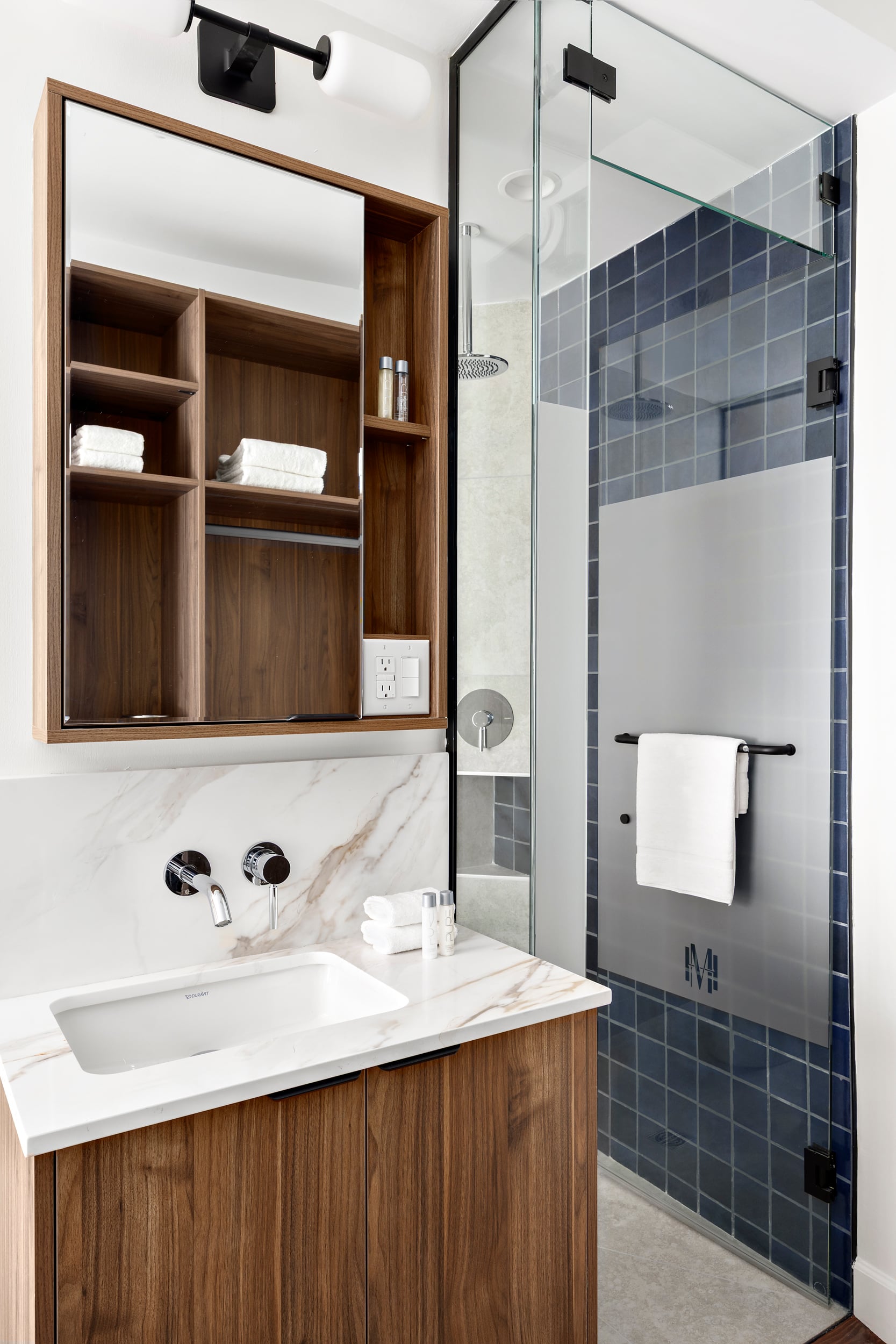 Compact guest bathroom with wood vanity and walk-in shower at Hotel Modo Vancouver